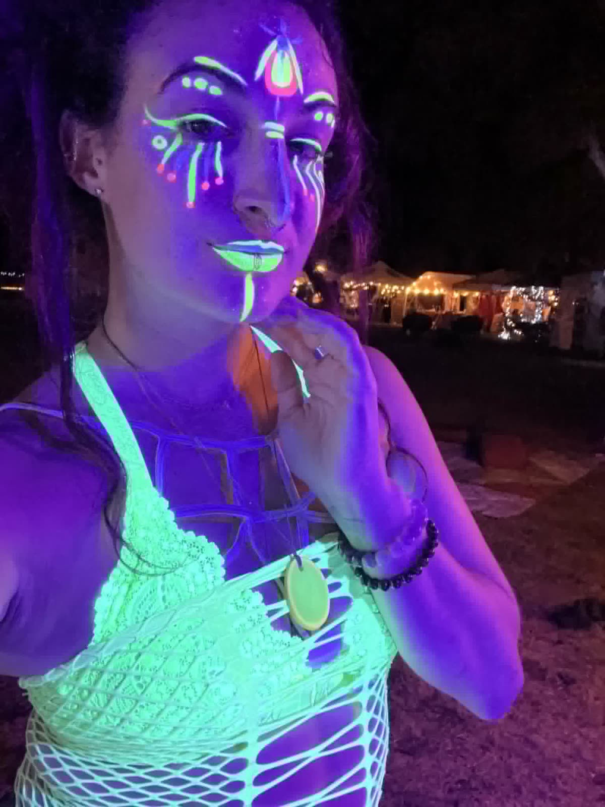 UV face paint markers glowing under blacklight — festival face design